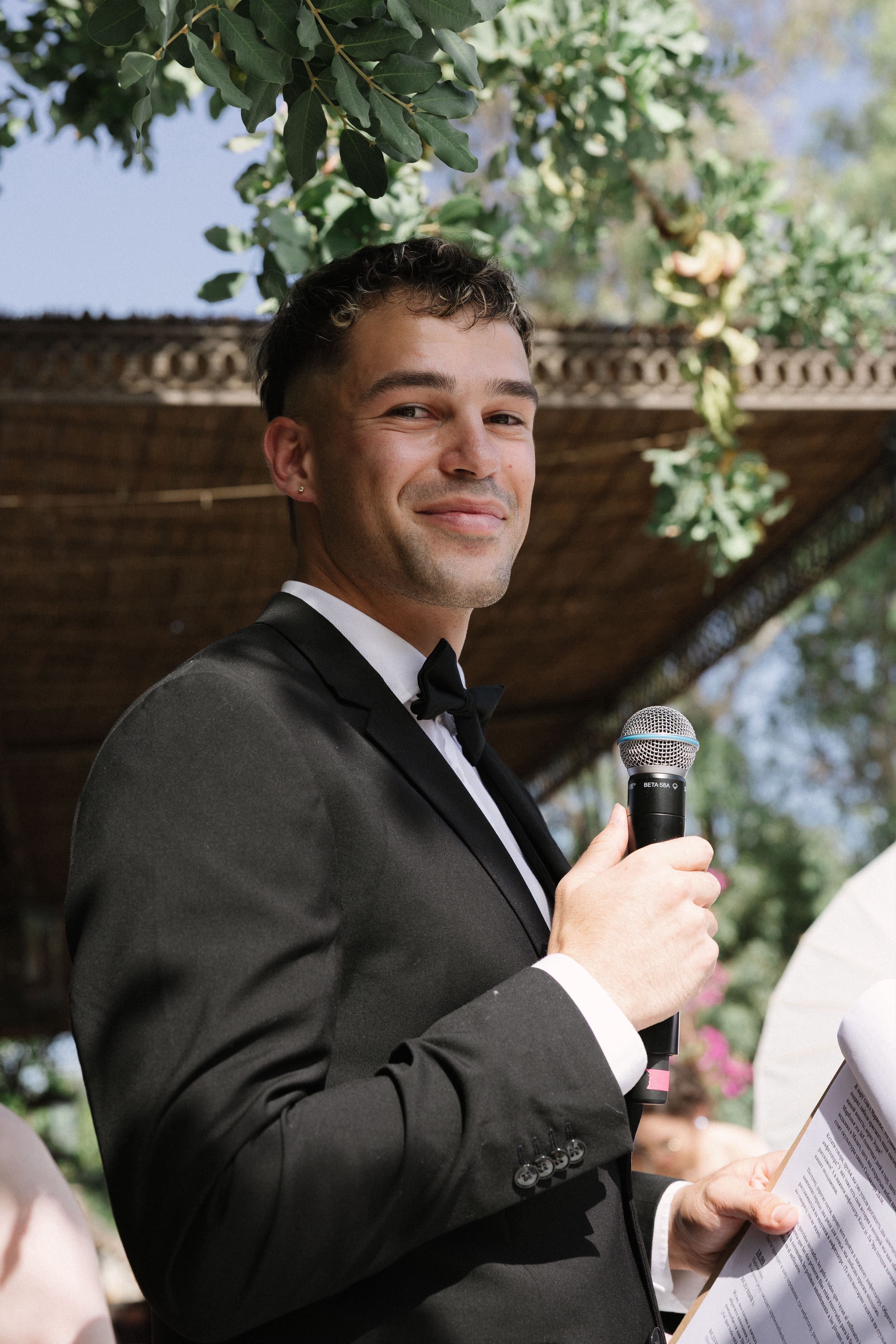Vova smiling with a microphone and notes during the wedding